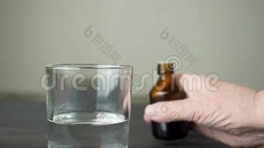 老年妇女用液体药物将药物滴入深色瓶子中的一杯水中