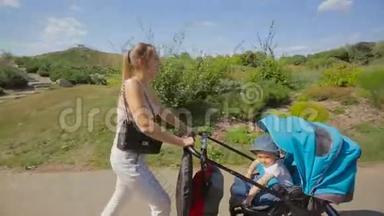 <strong>天气晴朗</strong>，美丽的年轻妈妈带着婴儿车在公园散步