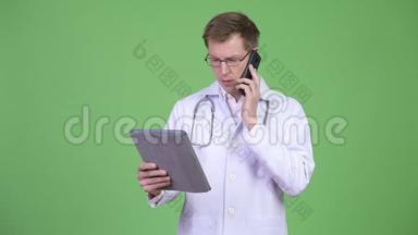 男子医生使用数码平板电脑，同时使用手机
