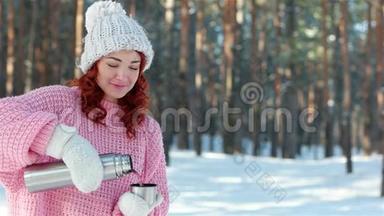 热饮寒冷的冬天，女孩从金属热水瓶里倒饮料，手里的热水瓶紧紧地拿着，手把茶倒进杯子里