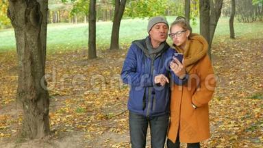 女儿和爸爸在秋天公园的视频上打电话。 爸爸微笑着和女儿一起笑