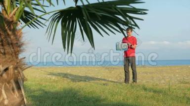 岩石海滩上的那个人。 前景中的棕榈树。 寻找正确路线图的游客
