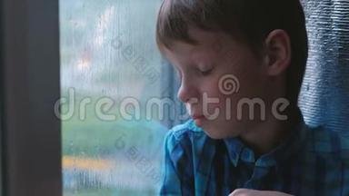 男孩在雨中看着窗外，很伤心。