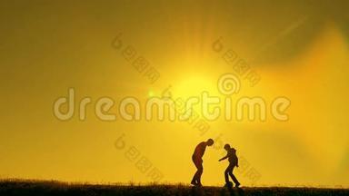 日落时分，父亲和儿子在公园里<strong>踢</strong>足球，在灿烂的阳光下剪影