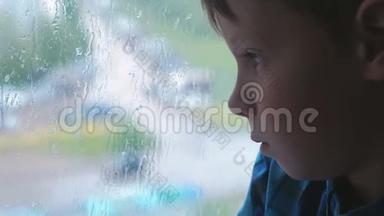 男孩在雨中<strong>看</strong>着<strong>窗外</strong>，很伤心。