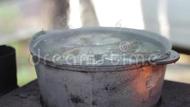 在烧木头的炉子上用金属锅煮鱼汤