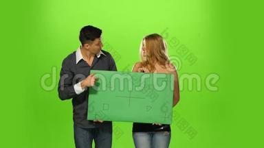 一对夫妇举着一个空白的牌子，绿色的屏幕