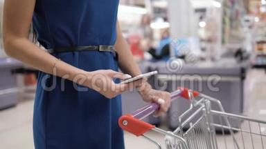 在超市购物时使用手机的女人，在购物中心购物店购物