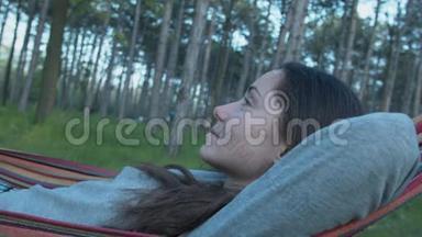 一个漂亮的女孩正在公园里的<strong>吊床</strong>上休息。 躺在花园<strong>吊床</strong>上的年轻女子