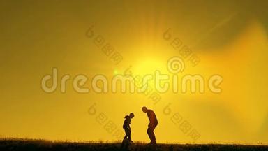 日落时分，父亲和儿子在公园里踢足球，在灿烂的阳光下剪影