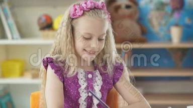 小女孩画了一支蓝色铅笔。 坐在书桌前画画的女孩。
