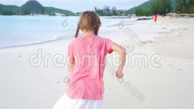 可爱的小女孩在海滩上奔跑。 快乐的孩子享受暑假。 慢动作