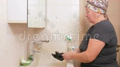 高级女人<strong>打扫</strong>酒店<strong>房间</strong>浴室的水槽。 她用手套和清洁剂。 在海绵的手里