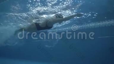 女游泳运动员在透明的游泳池里游泳，在游泳道上爬行