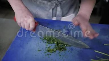 厨师`双手剁碎的绿色食品在一个商业厨房的板上装饰