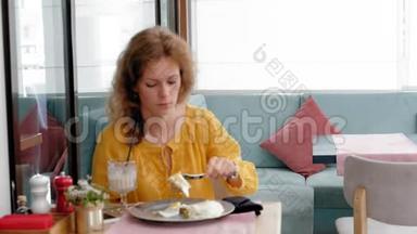 一位美丽的年轻女士在咖啡馆里用烤面包和鸡蛋吃早餐