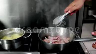 在炉子上煎洋葱的培根，厨师在设备齐全的厨房和餐厅准备一道菜