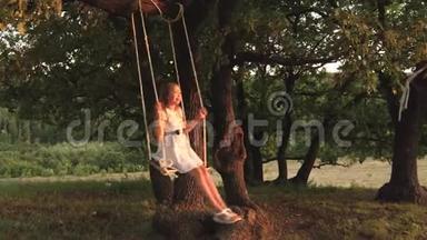 孩子们在公园的秋千上<strong>晒太阳</strong>。 年轻女孩在橡木树枝上的绳子上摆动。 少女喜欢飞行