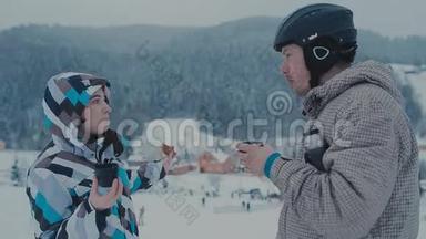 在山上滑雪期间茶歇。 在滑雪场喝茶的男人和女人