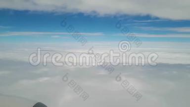 从飞机窗户上看到机翼、云层和地面，在云层上方飞行