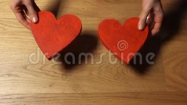 漂亮的女手把两个红色的心形放在木桌上。 爱，情人节`<strong>相聚</strong>，家庭，约会