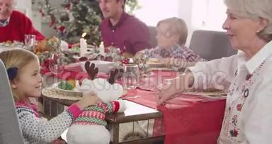 当一家人围坐在桌子旁，一起享用圣诞大餐时，孙女和祖母正在玩玩具驯鹿