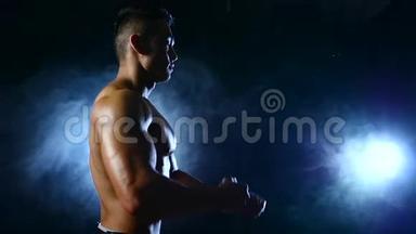 亚洲健美运动员展示了他的身体、力量和耐力。 <strong>黑烟</strong>背景。 慢动作
