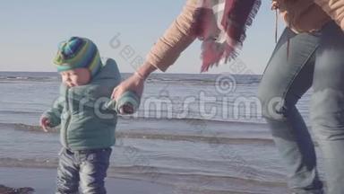 妈妈带着一个小孩沿着春天的海滩散步