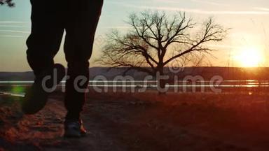 剪影人在日落时沿着道路<strong>奔跑</strong>，独自站在树上剪影。 在大自然中<strong>奔跑</strong>的运动青年