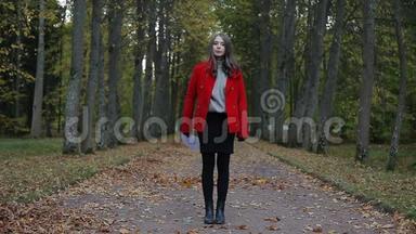 美丽的白种人女人，穿着红色外套，在秋天的森林里，用纸出售标语牌