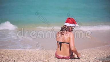 圣诞海滩度假圣诞老人帽子女人坐在沙滩上的天堂旅行目的地放松
