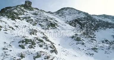 在冬天的雪山上向前飞，登山滑雪者走上登山。雪覆盖了群山