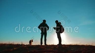 团队合作。 两名游客徒步<strong>旅行</strong>，男人和狗带着背包在日落时<strong>去</strong>徒步<strong>旅行</strong>。 慢动作视频。 智能手机
