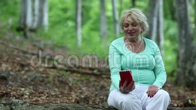 女人坐在森林中一棵倒下的树上，通过她的智能手机交流
