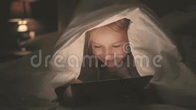 在黑暗的光线下，躺在床上的少女在<strong>社交网络</strong>上玩平板电脑。 特写小<strong>女孩</strong>看视频的画面