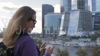 年轻女子用智能手机手机摄像头拍摄了一张高楼的照片。