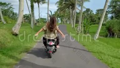 日落时分，一对幸福的夫妇在热带公路上骑摩托车绊倒。 户外拍摄的年轻夫妇骑摩托车。 男子