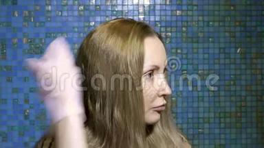 那个女人自己在家里涂着染发剂。 用一只手戴手套在头发上的绘画组合。 4k视频