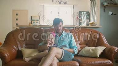 一位年轻英俊的父亲正坐在沙发上给他的宝贝女儿读一本<strong>故事</strong>书。 <strong>慢</strong>点，斯泰迪达姆