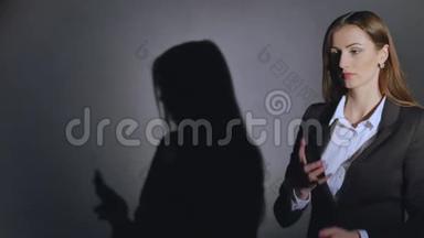 年轻优雅的女人在黑色背景下用手机和阴影说话