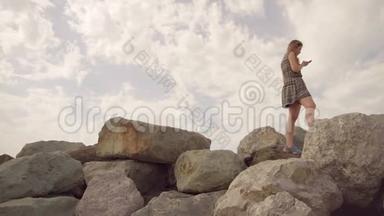 女孩走在山顶上，平衡在一个狭窄的山顶上，手里拿着一部手机
