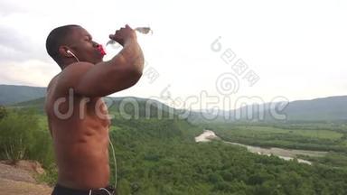 户外运动训练后非裔美国人肌肉男饮水的侧视。 呼吸绿色