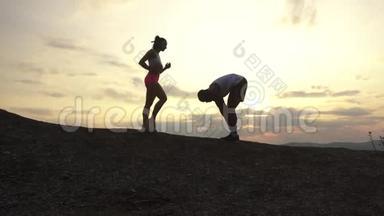混合种族的剪影组合健身教练在岩石山的背景下进行户外运动