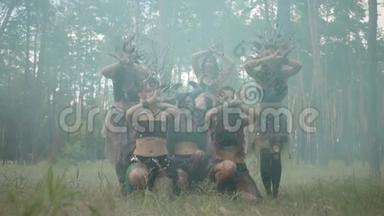 一群身穿化妆和神秘服装的女舞者在彩色烟雾中翩翩起舞。 森林