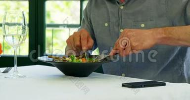 男人品尝他的菜，使用智能手机