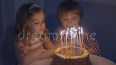 一个小男孩和一个女孩在一个庆祝蛋糕上看许愿，然后在蛋糕上吹蜡烛