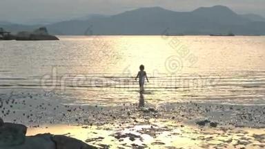 小女孩在日落的低潮时沿着湿沙滩奔跑