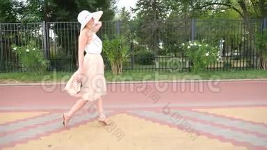 一个戴着帽子，穿着白色风装的优雅女人漫步在海滨.. 一般射击。 4k，慢镜头