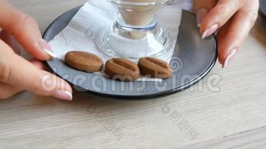 女人正在咖啡馆里端着一个茶碟和一个拿铁玻璃杯，茶碟上放着一块咖啡豆形式的饼干