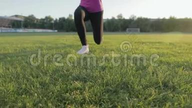 漂亮的健身女孩在体育场训练。 一个年轻的运动员在足球球门中在球场上绕圈子